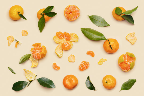 成熟新鲜的橙黄橘，绿叶，整只切片，米色桌底，最小平面。柑橘、水果、橘子等设计元素，静物美学格局图片下载
