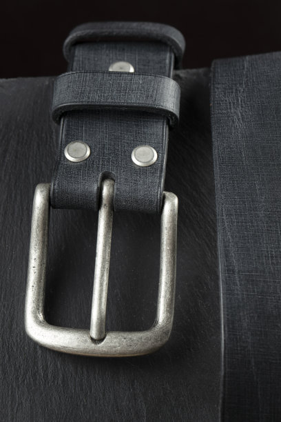 深色背景的黑色皮带。皮革产品。图片下载
