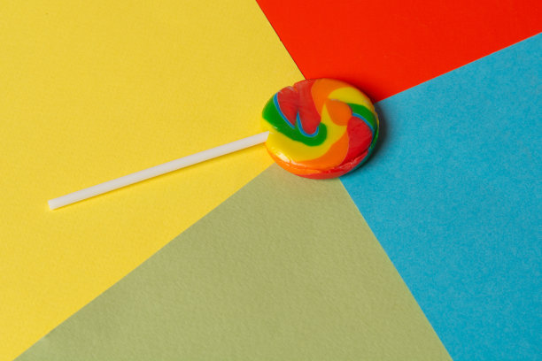 彩虹棒棒糖在彩色的背景上，在十字路口的中心一张张彩色纸板图片下载