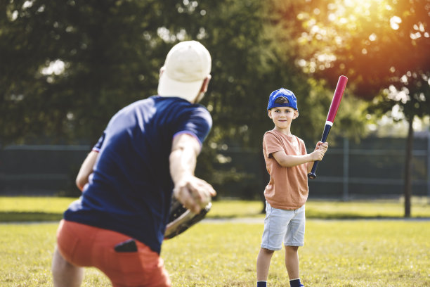 阳光明媚的日子里，父子俩在公园里打棒球图片下载