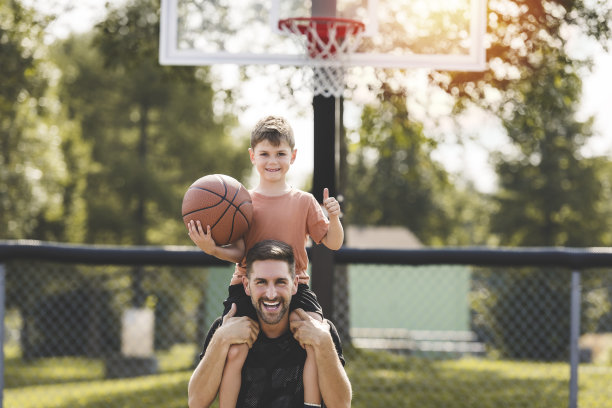 一个男人和一个小男孩在球场上打篮球，教小球员和花时间在户外图片下载