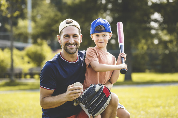 阳光明媚的日子里，父子俩在公园里打棒球图片下载