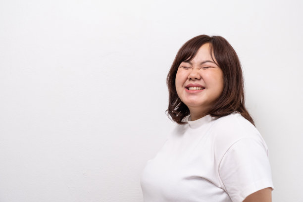 年轻美丽的亚洲超重妇女微笑与积极的情绪，感到高兴和自豪的身体尺寸。人像拍摄在白色背景与复制空间。图片下载