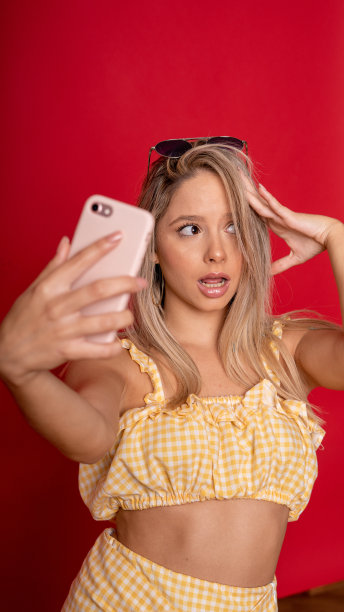 年轻迷人的白人女性与可爱的黄色露脐上衣和裙子正在自拍图片下载