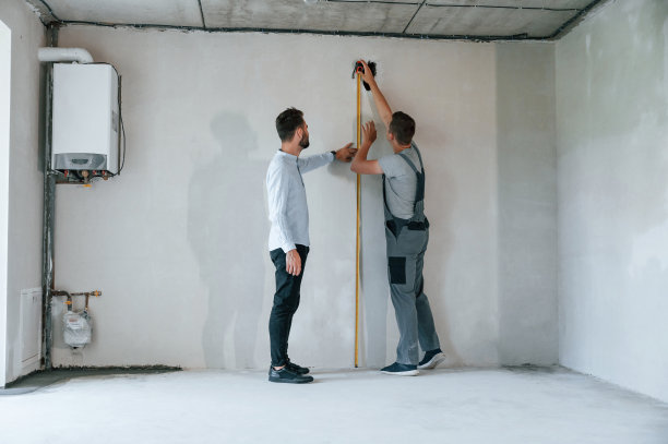 用滚筒测量墙体。两个人一起在公寓里修理图片下载