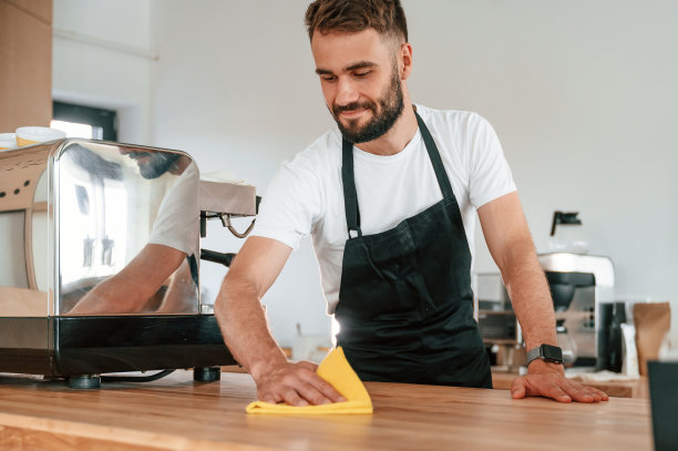 清洁桌子。穿着白衬衫和黑围裙的咖啡馆工作人员在室内图片下载