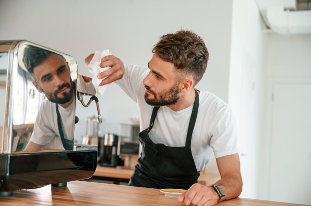 清洁咖啡机。穿着白衬衫和黑围裙的咖啡馆工作人员在室内图片下载
