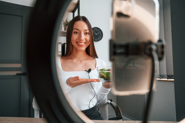 营养学家在镜头前展示沙拉。穿着白色衣服的年轻漂亮的女人在办公室里图片下载