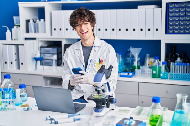 年轻的西班牙裔科学家在实验室使用智能手机和笔记本电脑图片下载