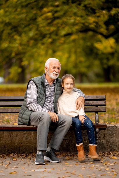 秋天的一天，爷爷和孙女坐在公园的长凳上图片下载