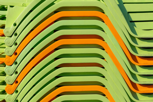 堆叠在海边的绿色和橙色沙滩躺椅作为度假背景图片下载