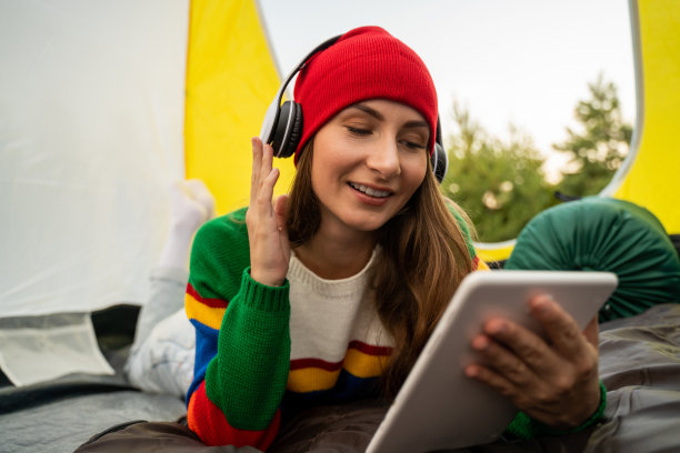 戴着红帽子的美女坐在旅游帐篷里，戴着耳机听音乐图片下载