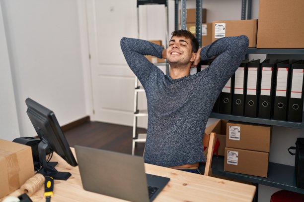 年轻的西班牙人电子商务工作人员放松，双手放在头上在办公室图片下载