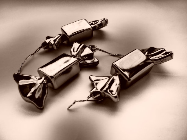 以糖果的形式装饰圣诞节。三颗装在包装纸里的糖果。为新年和圣诞节准备的不寻常的漂亮装饰品。挂线程。深褐色米色单色调。图片下载