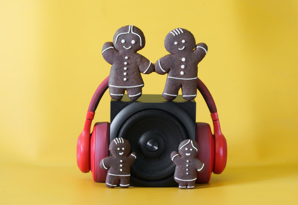 配有金属格栅的黑色扬声器、耳机和黄色背景上有趣的姜饼人。节日派对的概念，流行音乐，家庭和儿童的音频广播。图片下载