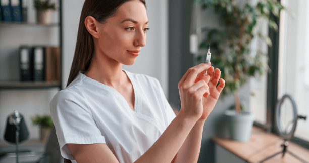 拿着注射器。穿着白大褂的年轻漂亮的女医生在办公室图片下载