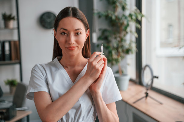 站着拿着注射器。穿着白大褂的年轻漂亮的女医生在办公室图片下载
