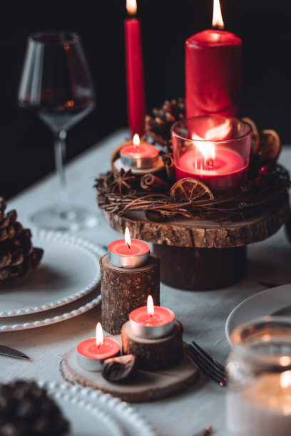 圣诞或新年家庭晚餐的乡村餐桌装饰。配红蜡烛，干橙，圆锥形，肉桂，八角。零废物环保家居。舒适的氛围，深色的背景。近距离图片下载