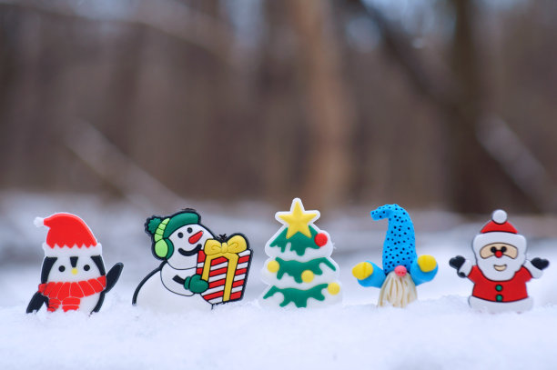 有礼物的雪人雕像，一个小矮人，一只企鹅和圣诞老人在雪地背景上。图片下载