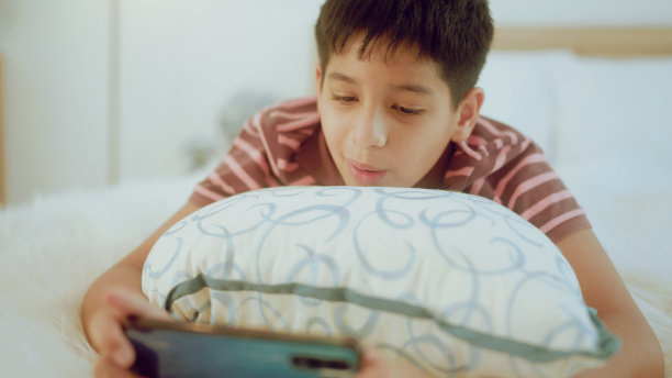 一个印度年轻人在家里玩智能手机游戏。图片下载