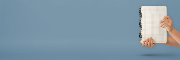 手提记事本。蓝色背景的空白记事本。手拿着一本没有文字的书。那个女孩正拿着一本空封面的书。图片下载