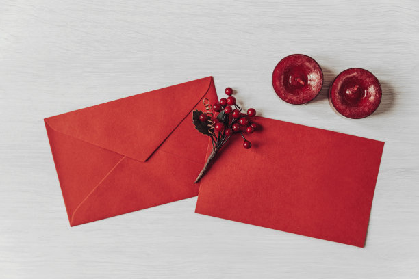 白色木质背景的冬青浆果和蜡烛的信封和贺卡图片下载
