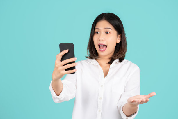 美丽的亚洲女人。她被电话吓到了
年轻美丽的亚洲女性的肖像照片感到高兴或惊讶震惊，看着智能手机图片下载