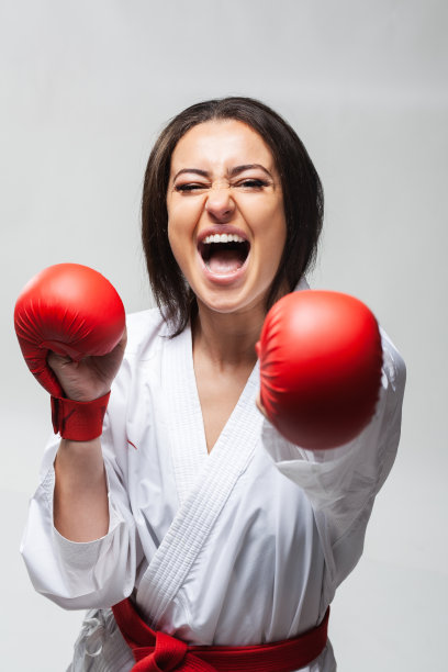 肖像尖叫空手道女孩在和服和红色手套踢向相机图片下载