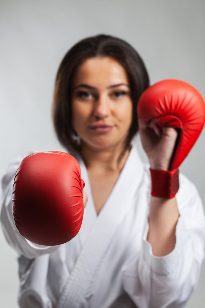 空手道女孩的肖像和服和红色手套给踢向相机图片下载