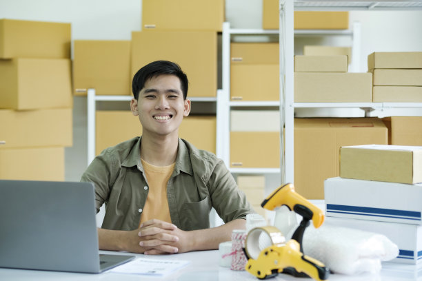 年轻的男性网络企业主一边工作一边看着相机。图片下载