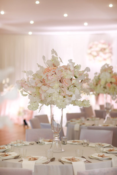 喜庆的婚礼装饰。在婚礼当天，餐桌上的玻璃花瓶里插着美丽新鲜的白色和粉色花朵。高画质照片图片下载