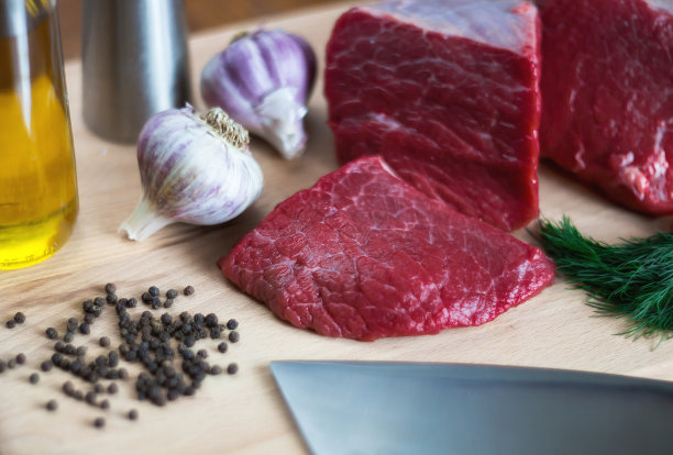 一块新鲜的牛肉，辣椒和香草放在砧板上。一块肉的特写。在家里做饭的概念或咖啡馆和餐馆的菜单。图片下载