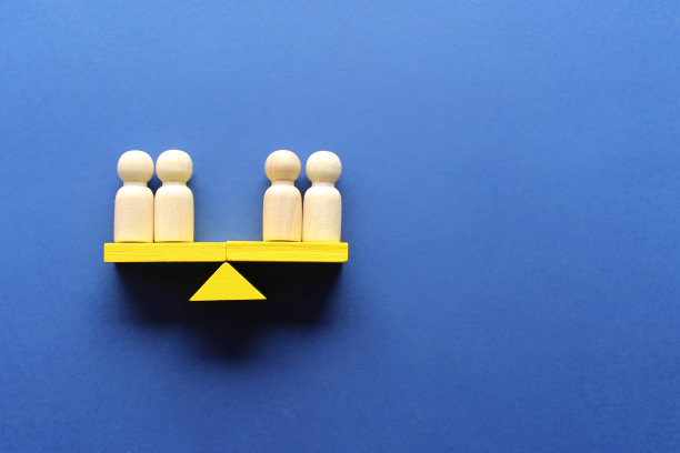 平衡秤上的木制洋娃娃。图片下载