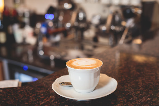 咖啡师在咖啡屋酒吧的咖啡机前工作，调酒师在制作卡布奇诺或拿铁，调酒师在咖啡馆柜台准备咖啡饮料图片下载