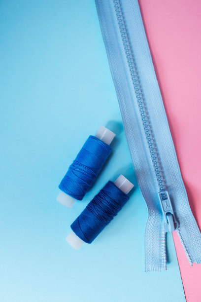 工作地点裁缝。缝纫是我的爱好。粉色和蓝色背景的衣服拉链。图片下载