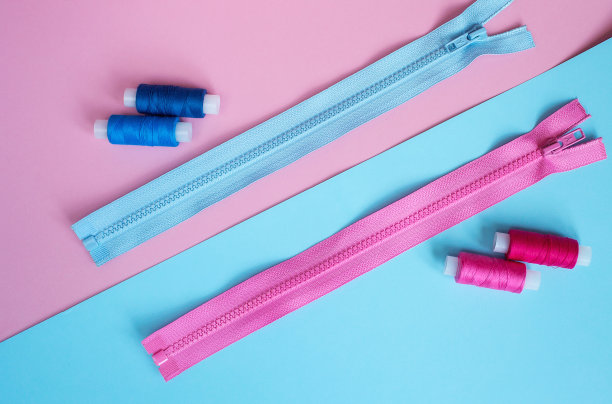 工作地点裁缝。缝纫是我的爱好。粉色和蓝色背景的衣服拉链。图片下载