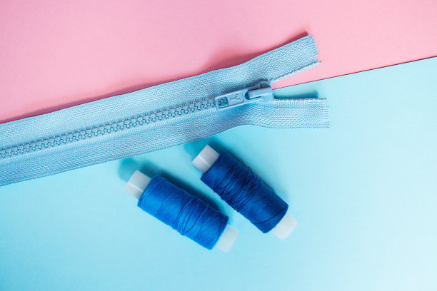 工作地点裁缝。缝纫是我的爱好。粉色和蓝色背景的衣服拉链。图片下载