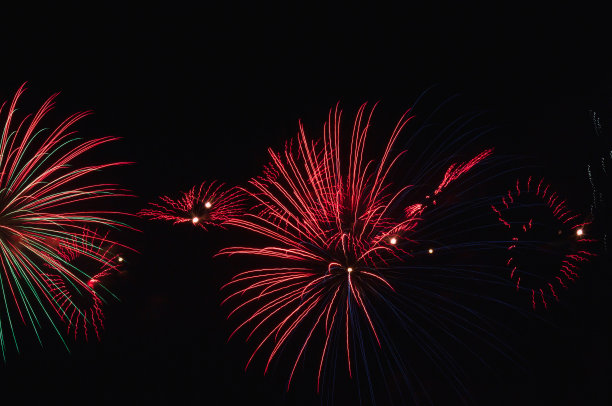 明亮的彩色烟花衬托在漆黑的夜空上。庆祝烟花。天空中明亮的灯光。新年的烟花。图片下载
