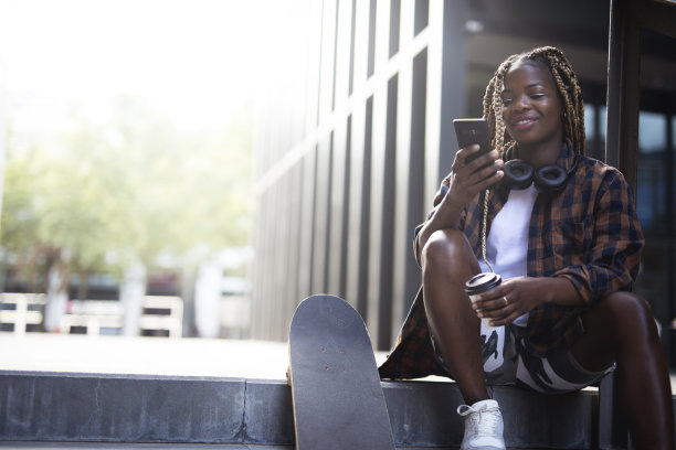 年轻时尚的女人用滑板玩手机图片下载
