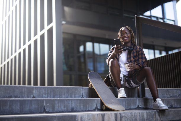 年轻时尚的女人用滑板玩手机图片下载