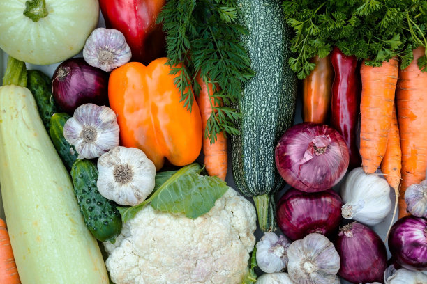 柳条篮子里装满了新鲜的生蔬菜。绿色草坪上的一篮子蔬菜(花椰菜、胡萝卜、黄瓜、西红柿、西葫芦、辣椒、大蒜和洋葱)。秋季作物，采集或收获。图片下载