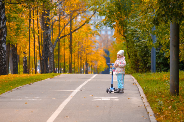 秋天的一天，小女孩骑着三轮车在秋天的公园里。图片下载