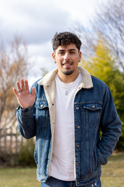 一个微笑着挥手的年轻拉丁人的垂直肖像。视频通话画面图片下载