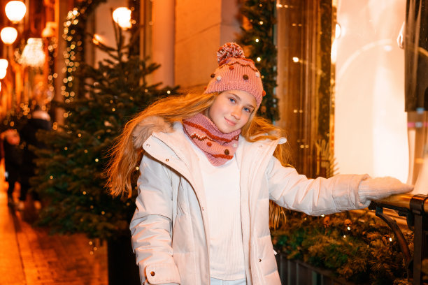 一个十几岁的女孩在一个节日的夜晚在冬天的街上图片下载