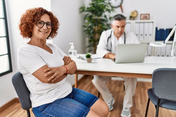 老年妇女坐在医生预约开心的脸微笑着交叉双臂看着相机。积极的人。图片下载