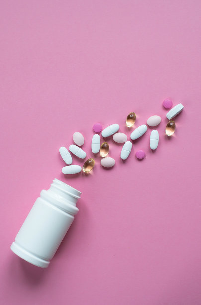 各种各样的药物药丸，药片和粉红色背景的白色瓶子。文本的复制空间。图片下载