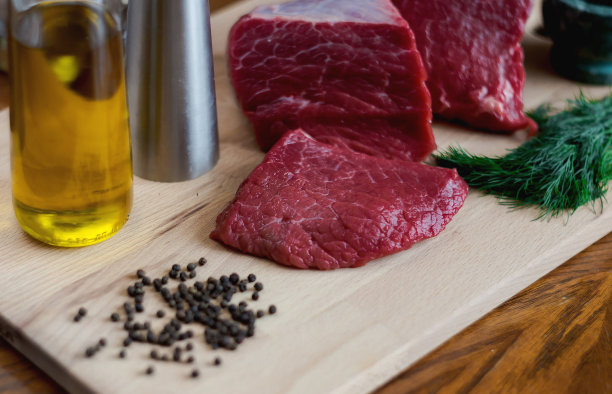 一块新鲜的牛肉，辣椒和香草放在砧板上。一块肉的特写。在家里做饭的概念或咖啡馆和餐馆的菜单。图片下载