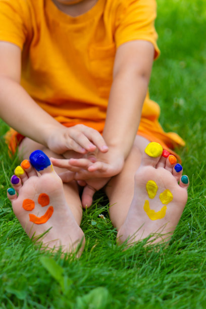 孩子们画着图案的脚在绿色的草地上微笑。有选择性的重点。图片下载