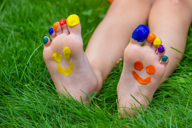 孩子们画着图案的脚在绿色的草地上微笑。有选择性的重点。图片下载