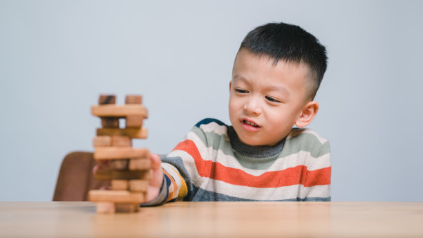 快乐的亚洲男孩在玩木制积木叠乐。享受乐趣，学习创造力。聪明孩子的概念。5岁。图片下载